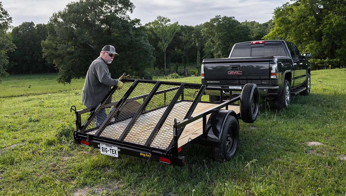 a gmc truck is pulling a 30sa utility trailer in a grassy field