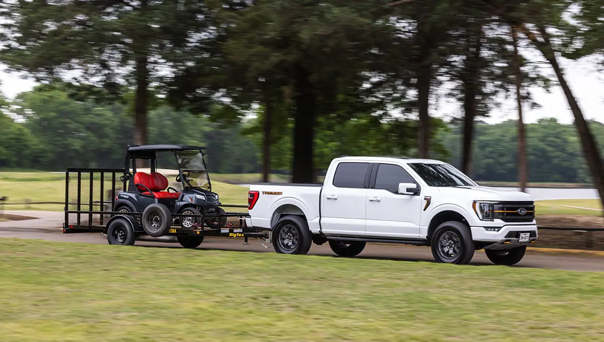 a white truck is towing a golf cart on a 35sa trailer