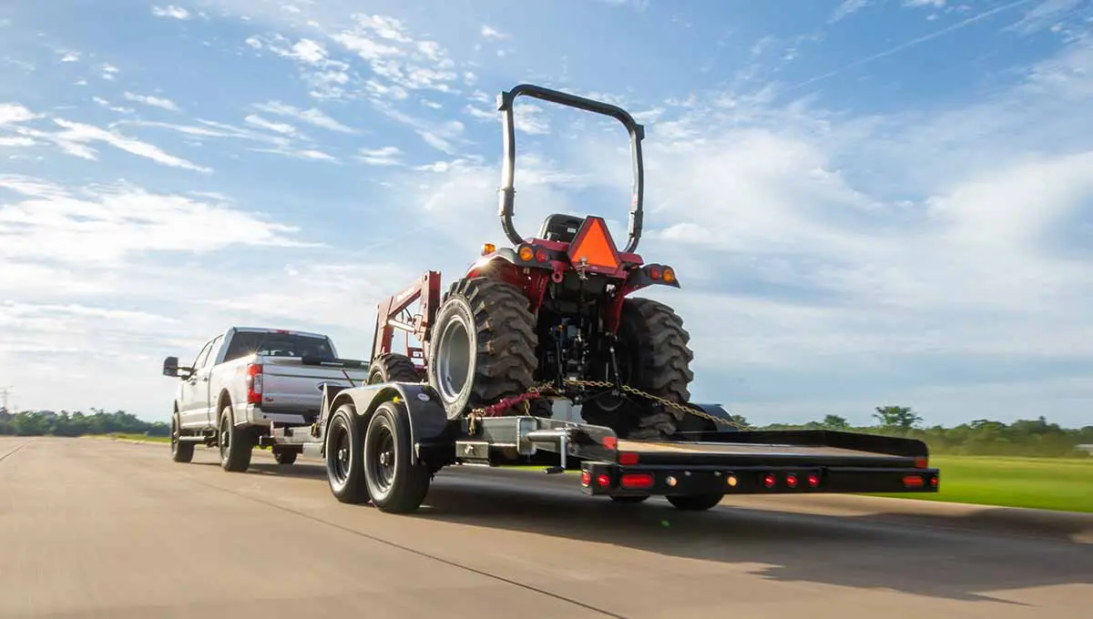 a truck is pulling a 10ch car hauler trailer with a tractor on it