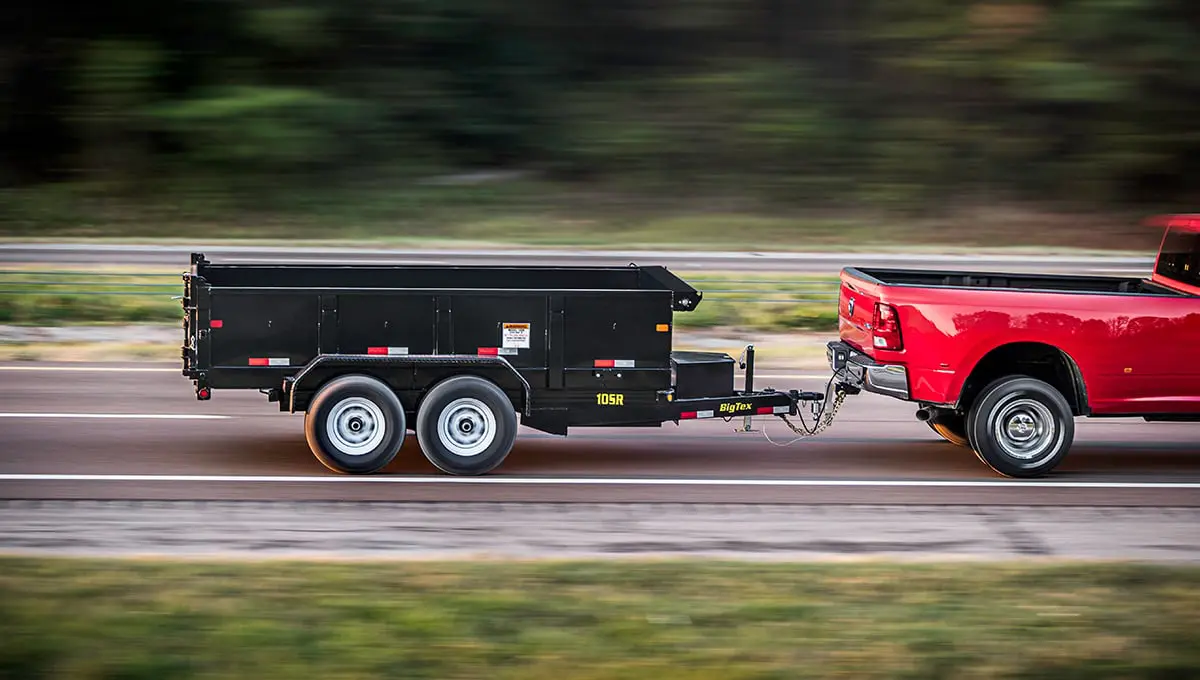 a red truck is pulling a 10sr dump trailer with a yellow sticker on it that says ' gator '