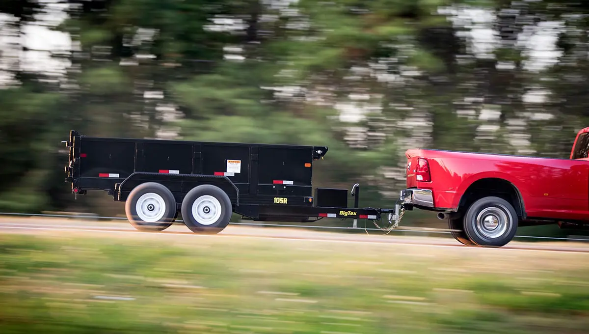 a red truck is pulling a 10sr dump trailer that says big tire