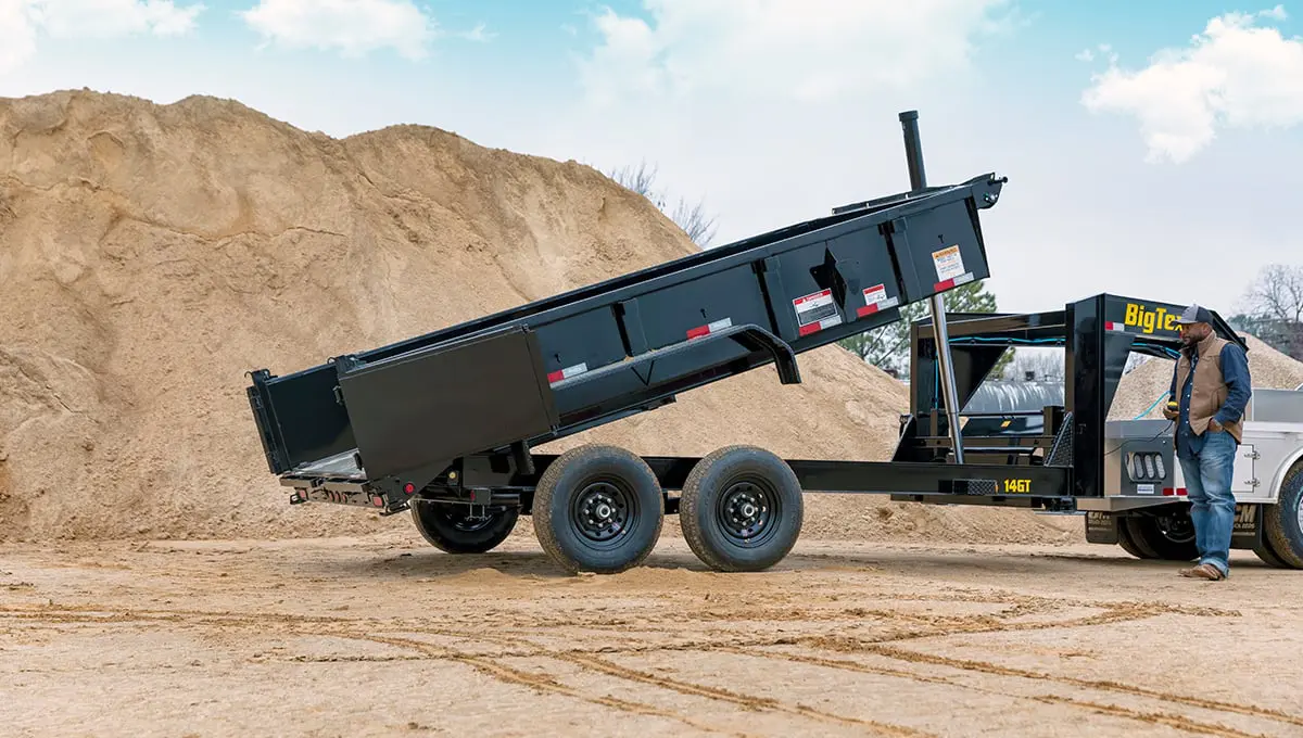 a man is standing next to a 14gt commercial grade big tex dump trailer