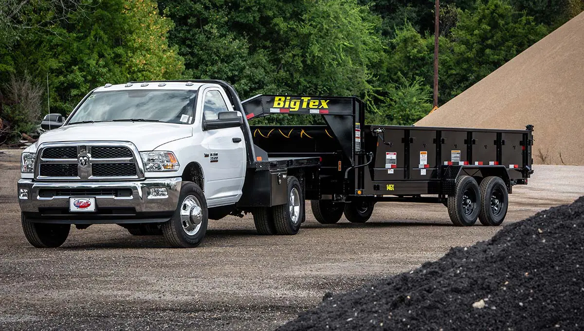 a ram truck is pulling a 14gx commercial grade dump big tex trailer