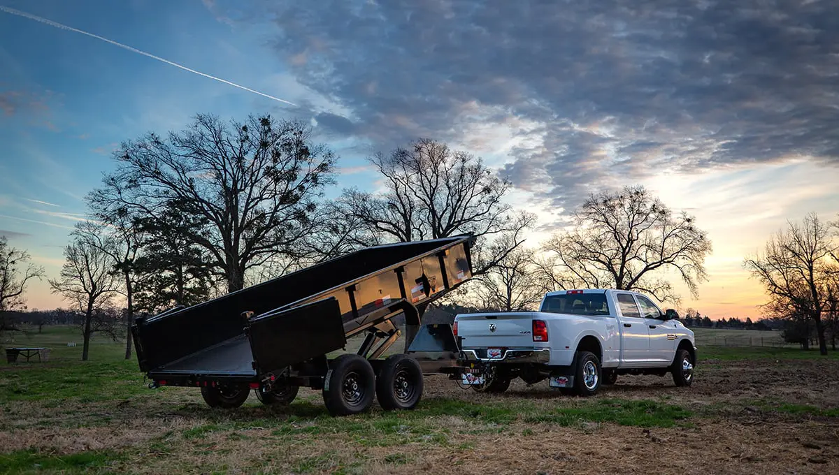 a white ram truck is pulling a 14lp commercial grade dump trailer