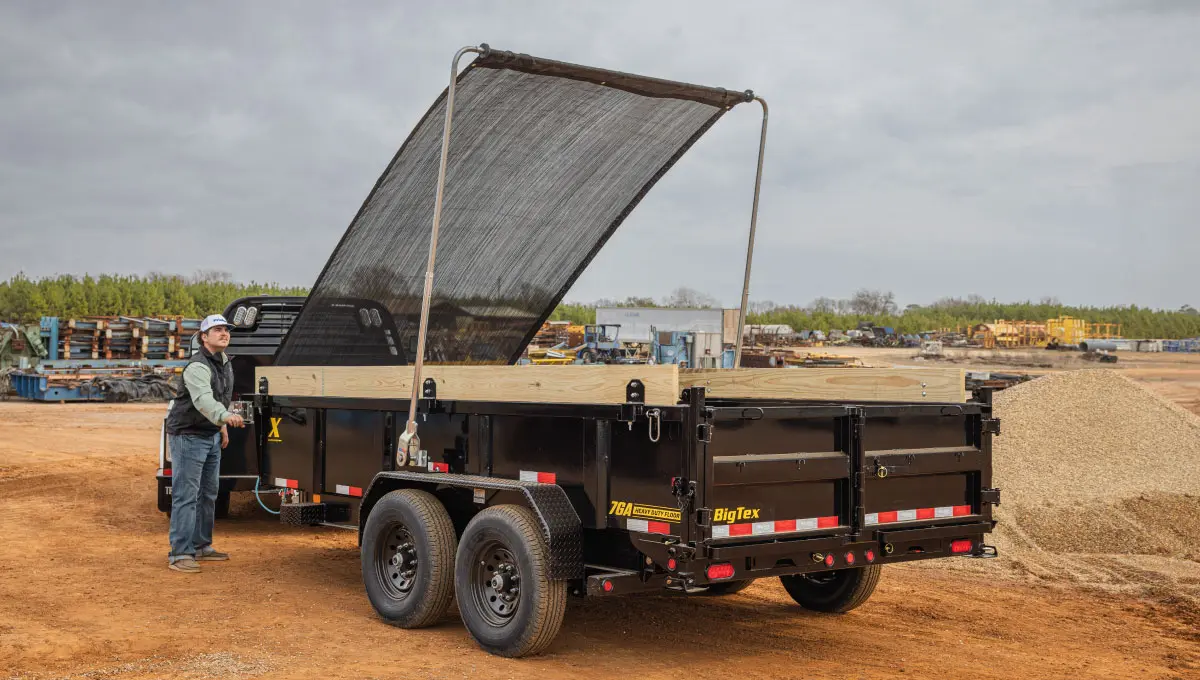 a man standing next to a dump trailer that says big tex