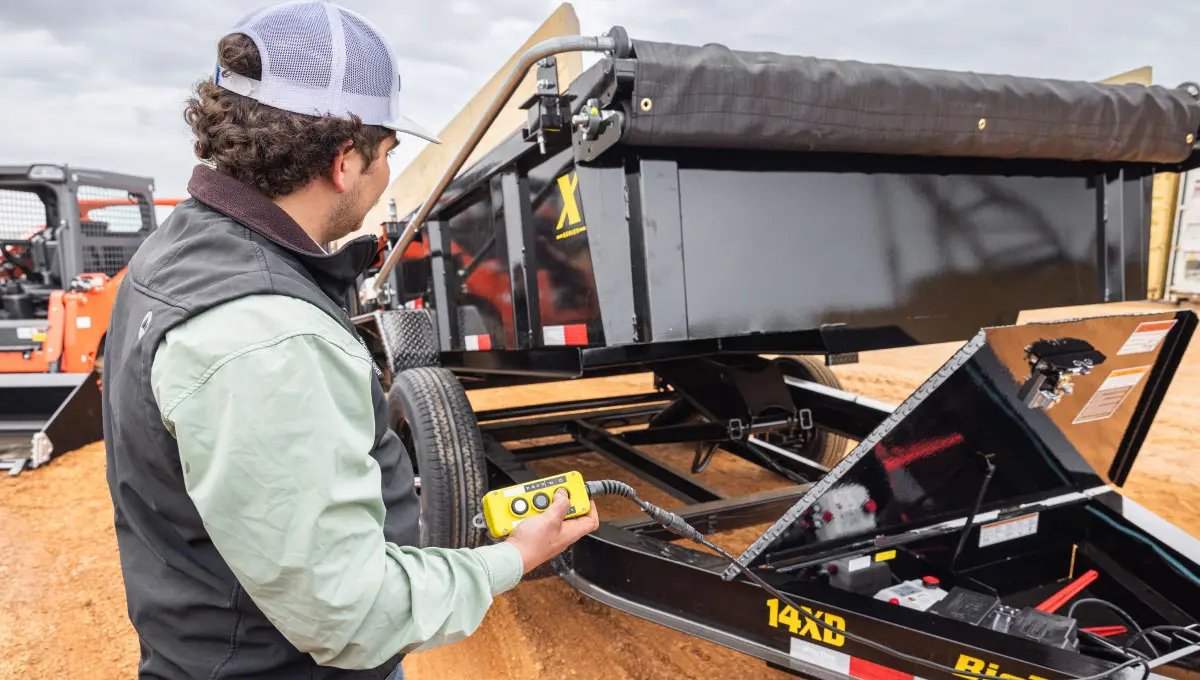 a man is holding a remote control in front of a trailer that says 14x3