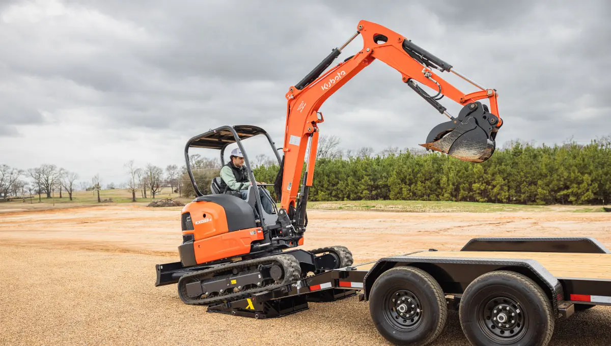 a man is driving a small orange kubota excavator