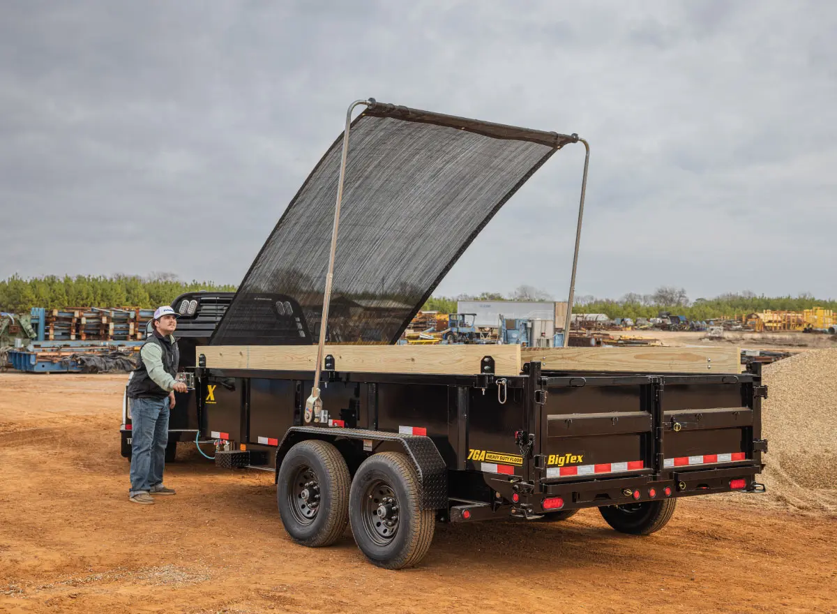 a man standing next to a dump trailer that says big tex