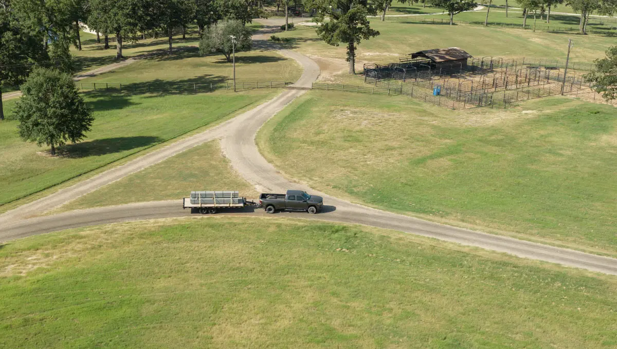 14OE Big Tex Trailer hitched to truck driving through farm