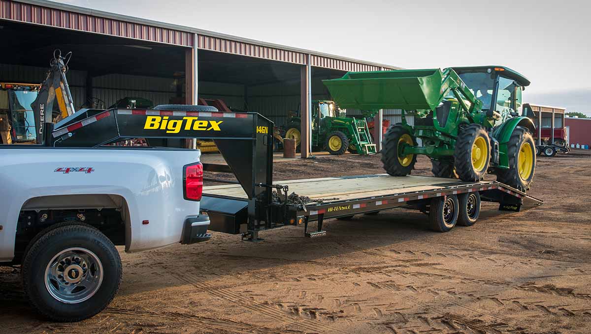 14GN flatbed gooseneck trailer carrying construction vehicle