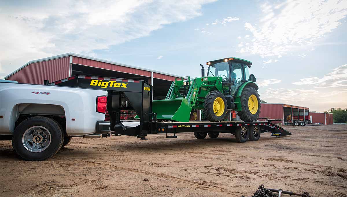 14GN flatbed gooseneck trailer carrying green construction vehicle